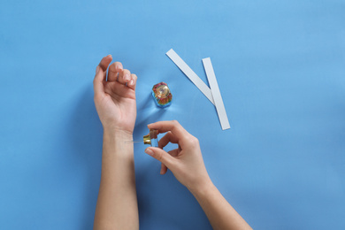 Photo of Woman applying perfume on blue background, top view