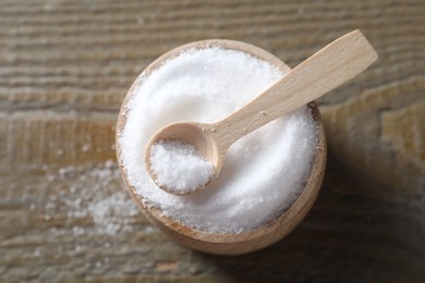 Photo of Organic salt in bowl and spoon on wooden table, top view