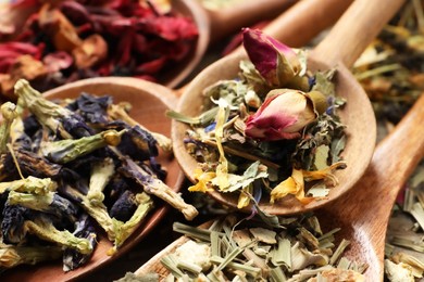 Wooden spoons with different teas on table, closeup