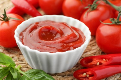 Bowl of tasty ketchup and ingredients on wicker mat, closeup