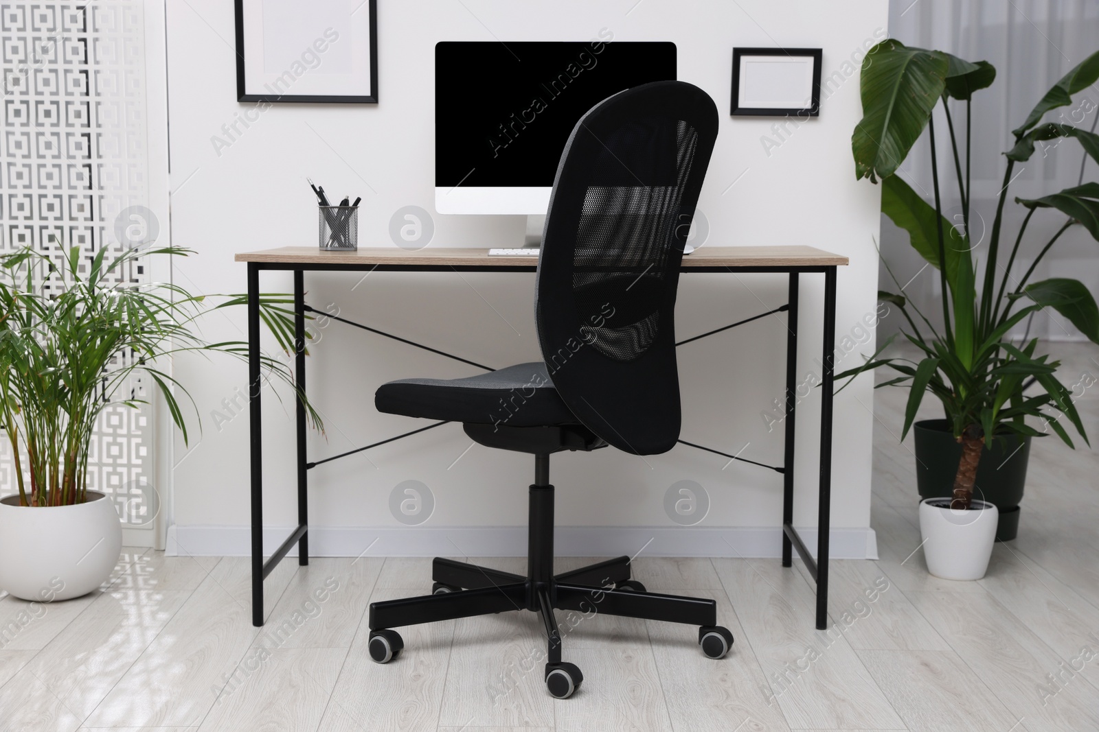 Photo of Stylish room interior with comfortable office chair, desk and houseplants