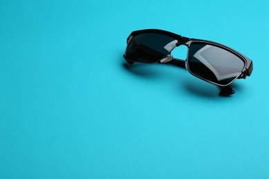 Photo of Stylish sunglasses on blue background, space for text. Fashionable accessory