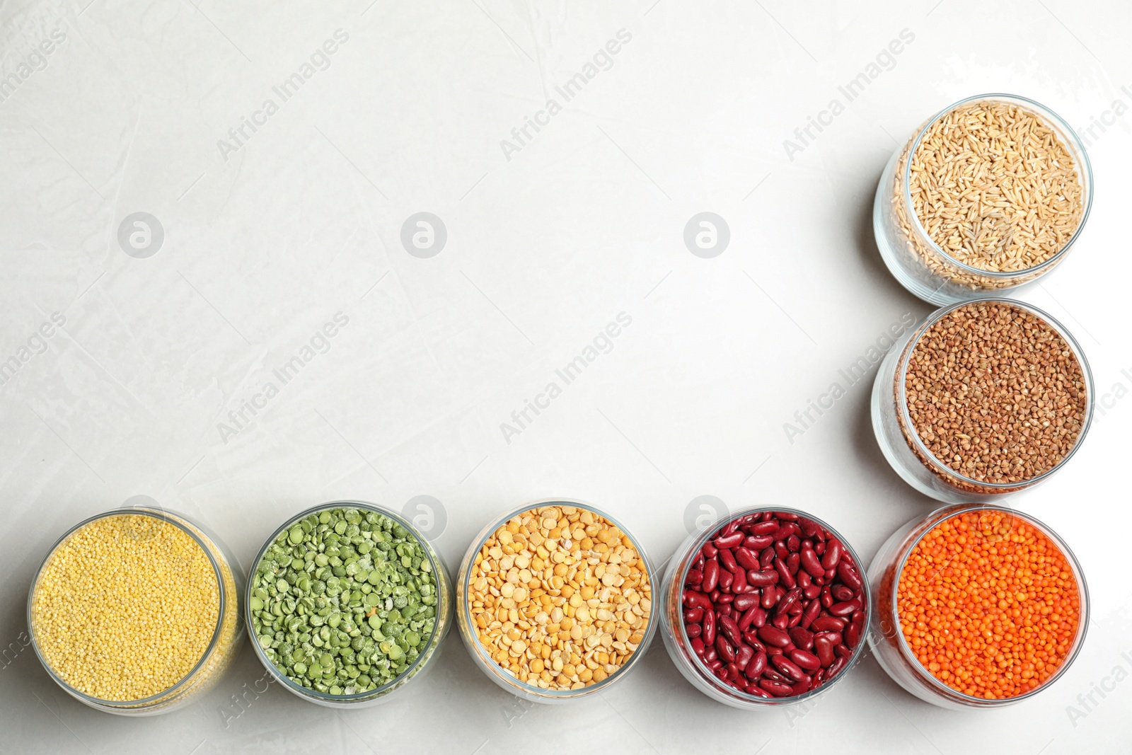 Photo of Jars with different cereals on white background, flat lay. Space for text