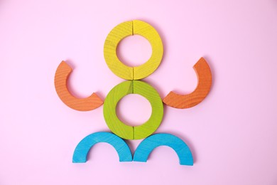 Colorful wooden pieces of playing set on pink background, flat lay. Educational toy for motor skills development