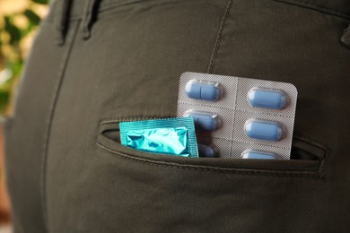 Photo of Jeans with pills and condom in pocket, closeup. Potency problem