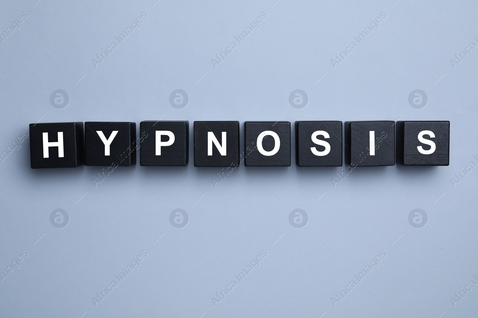 Photo of Black wooden blocks with word HYPNOSIS on light background, flat lay