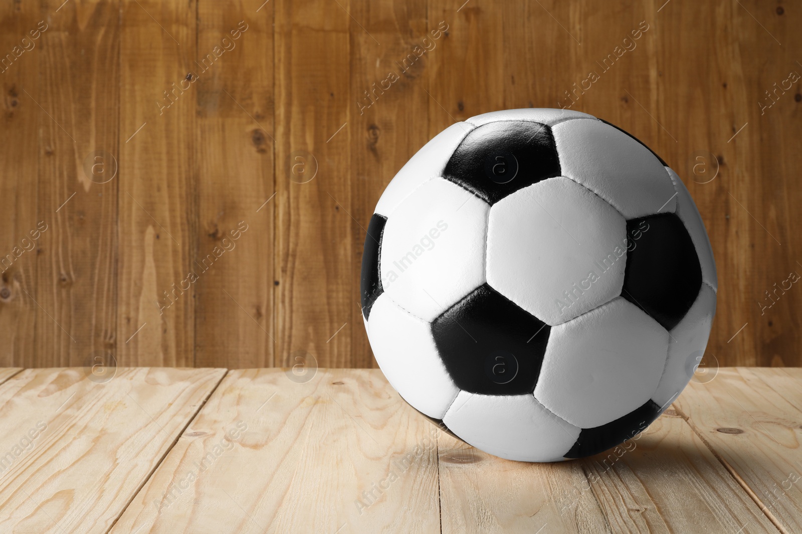 Photo of Soccer ball on wooden background, space for text