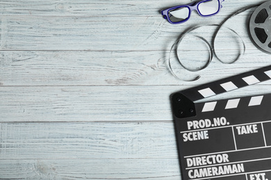 Photo of Flat lay composition with clapperboard, cinema reel and 3d glasses on white wooden table, space for text