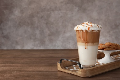Photo of Glass of caramel macchiato and tasty pastry on table, space for text