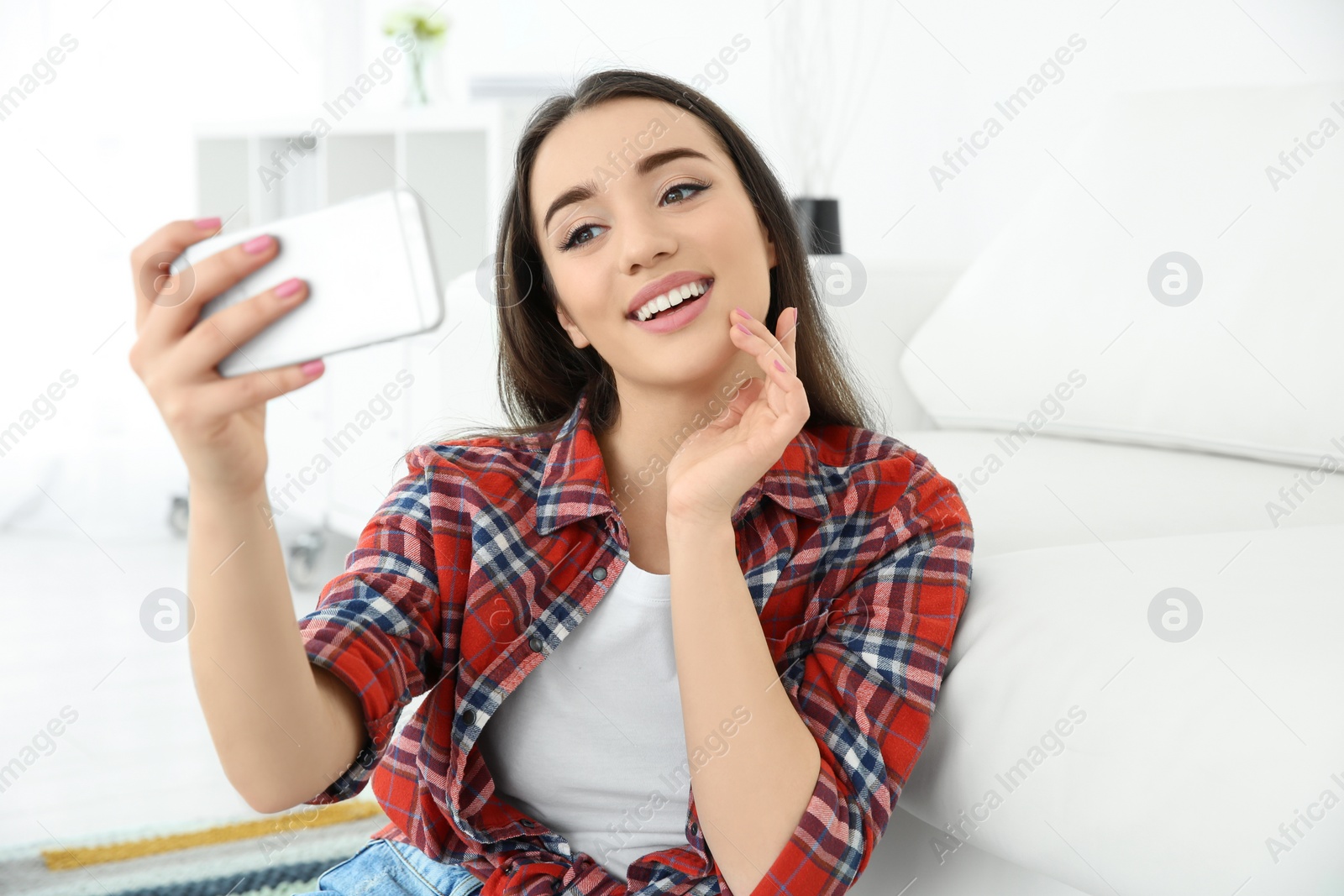 Photo of Beautiful young woman taking selfie at home