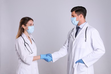 Doctors shaking hands on light grey background