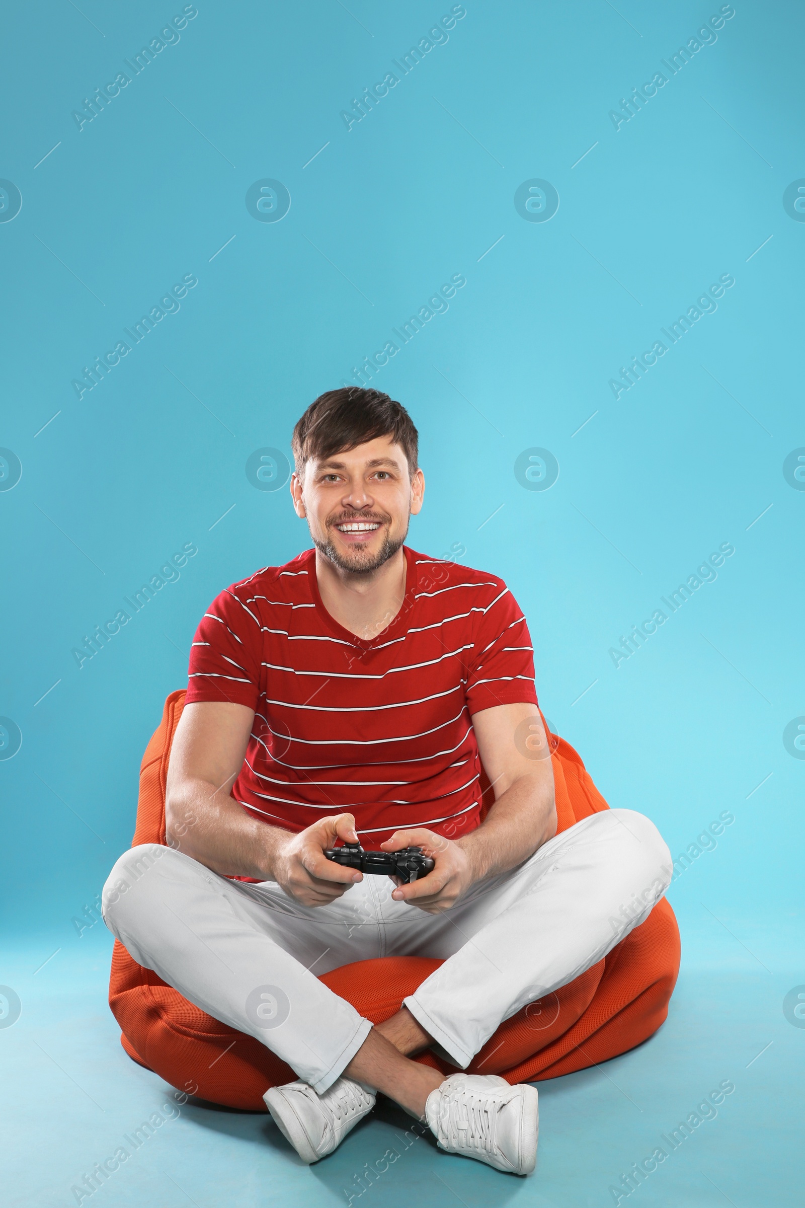 Photo of Emotional man playing video games with controller on color background. Space for text