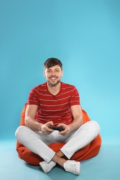 Photo of Emotional man playing video games with controller on color background. Space for text