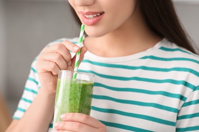 Young woman drinking tasty smoothie on grey background, closeup view