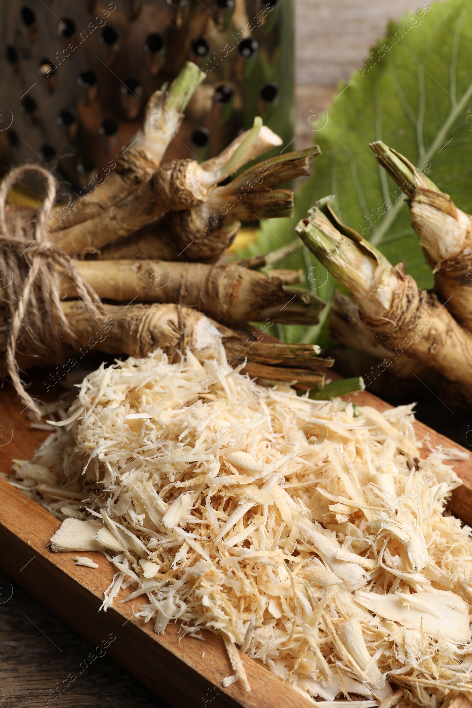 Photo of Grated horseradish and roots on table, closeup