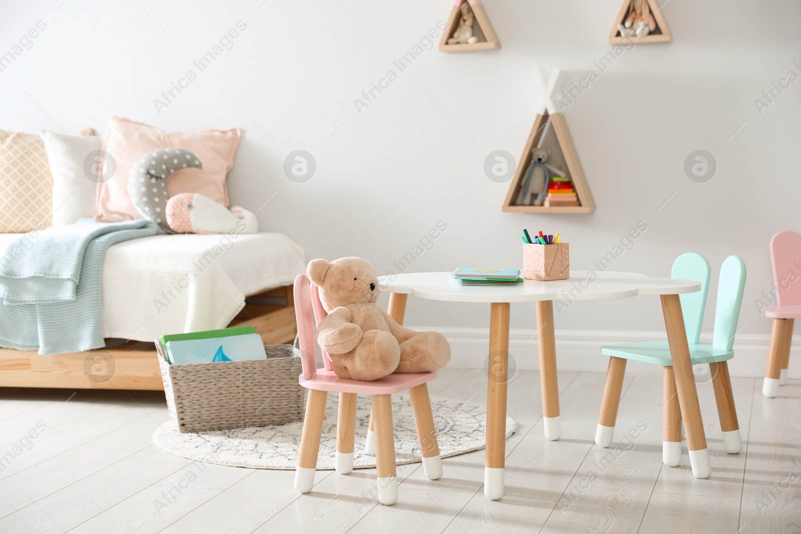 Photo of Small table and chairs with bunny ears in children's room interior