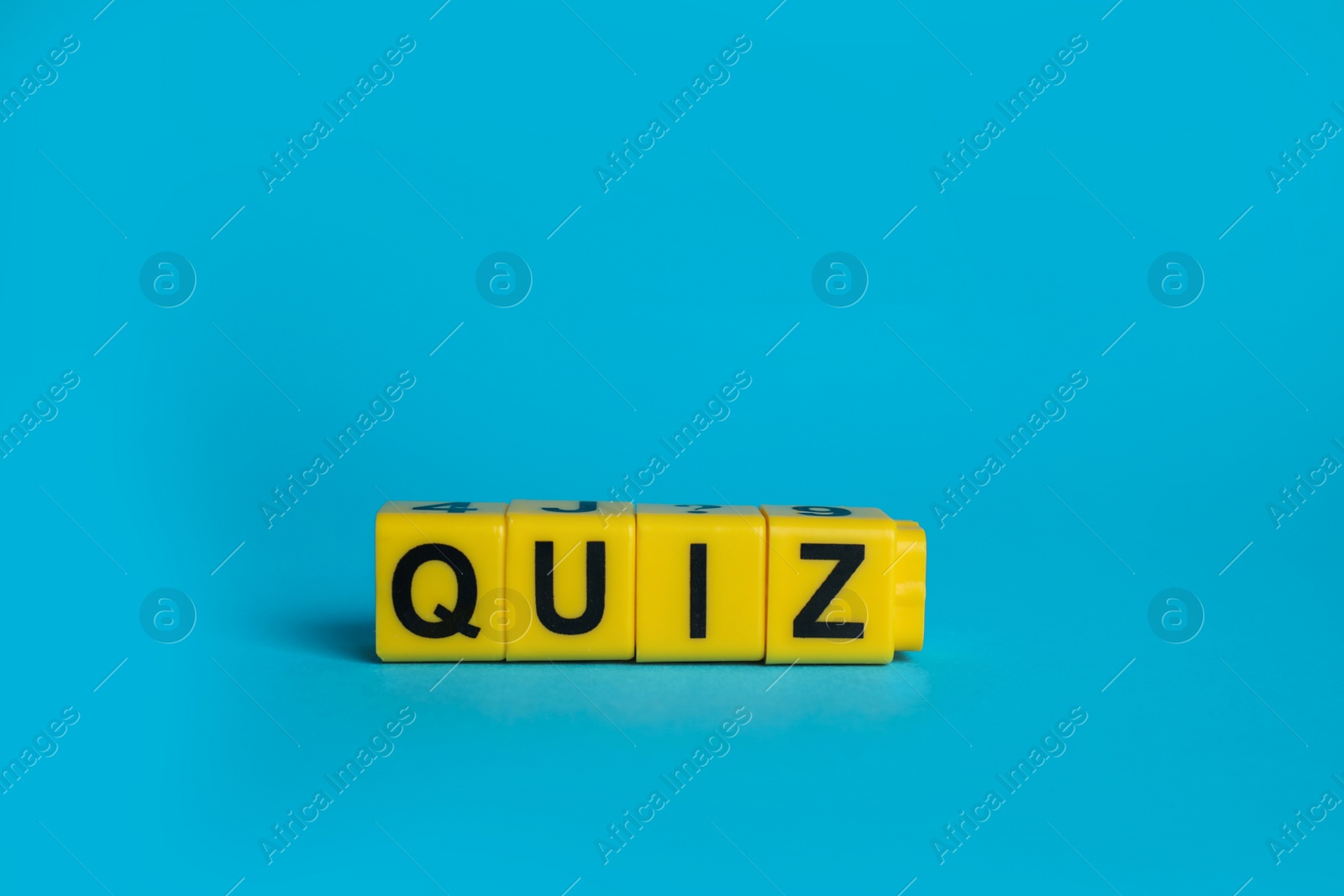 Photo of Yellow cubes with word Quiz on light blue background. Space for text