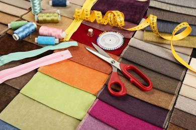 Photo of Different sewing accessories on colorful fabric samples