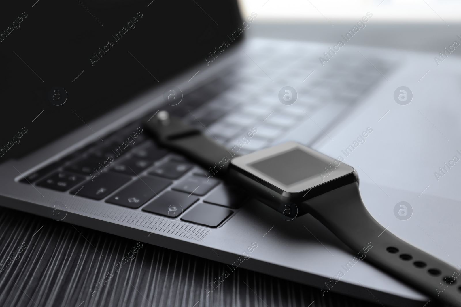 Stylish smart watch and laptop on table, closeup Photo of Stylish smart watch and laptop on table, closeup
