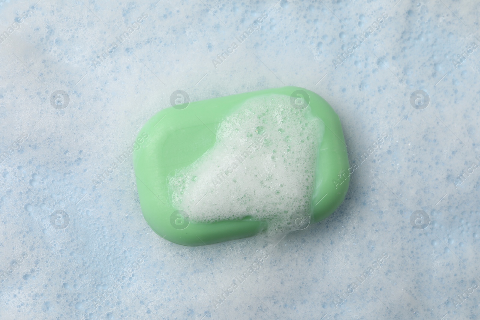 Photo of Soap and fluffy foam on light blue background, top view