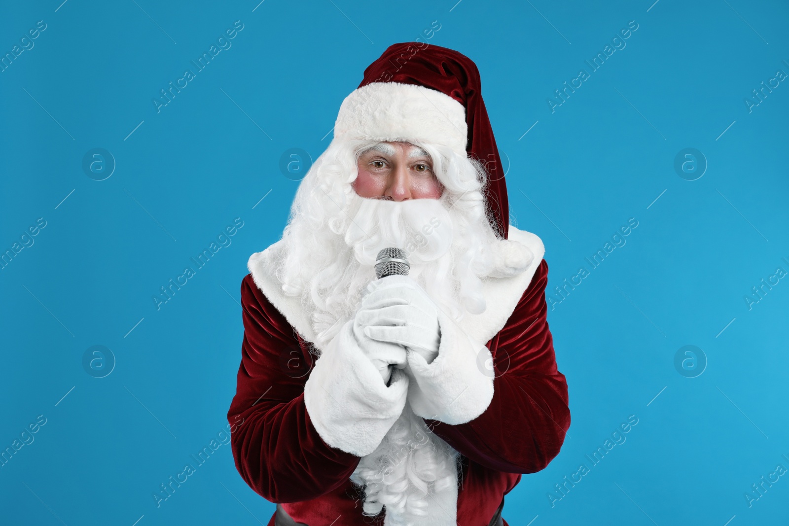 Photo of Santa Claus singing with microphone on blue background. Christmas music