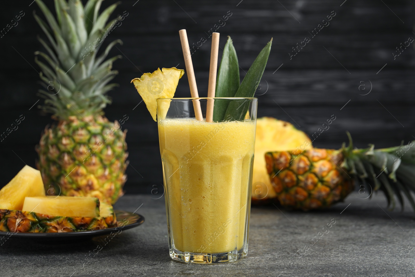 Photo of Tasty pineapple smoothie and sliced fruit on grey table, closeup