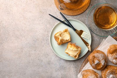 Photo of Delicious profiteroles filled with cream and tea on grey table, flat lay. Space for text