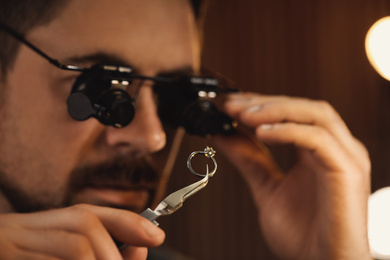 Photo of Jeweler working with ring on blurred background, closeup