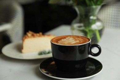 Cup of fresh coffee and dessert on table indoors