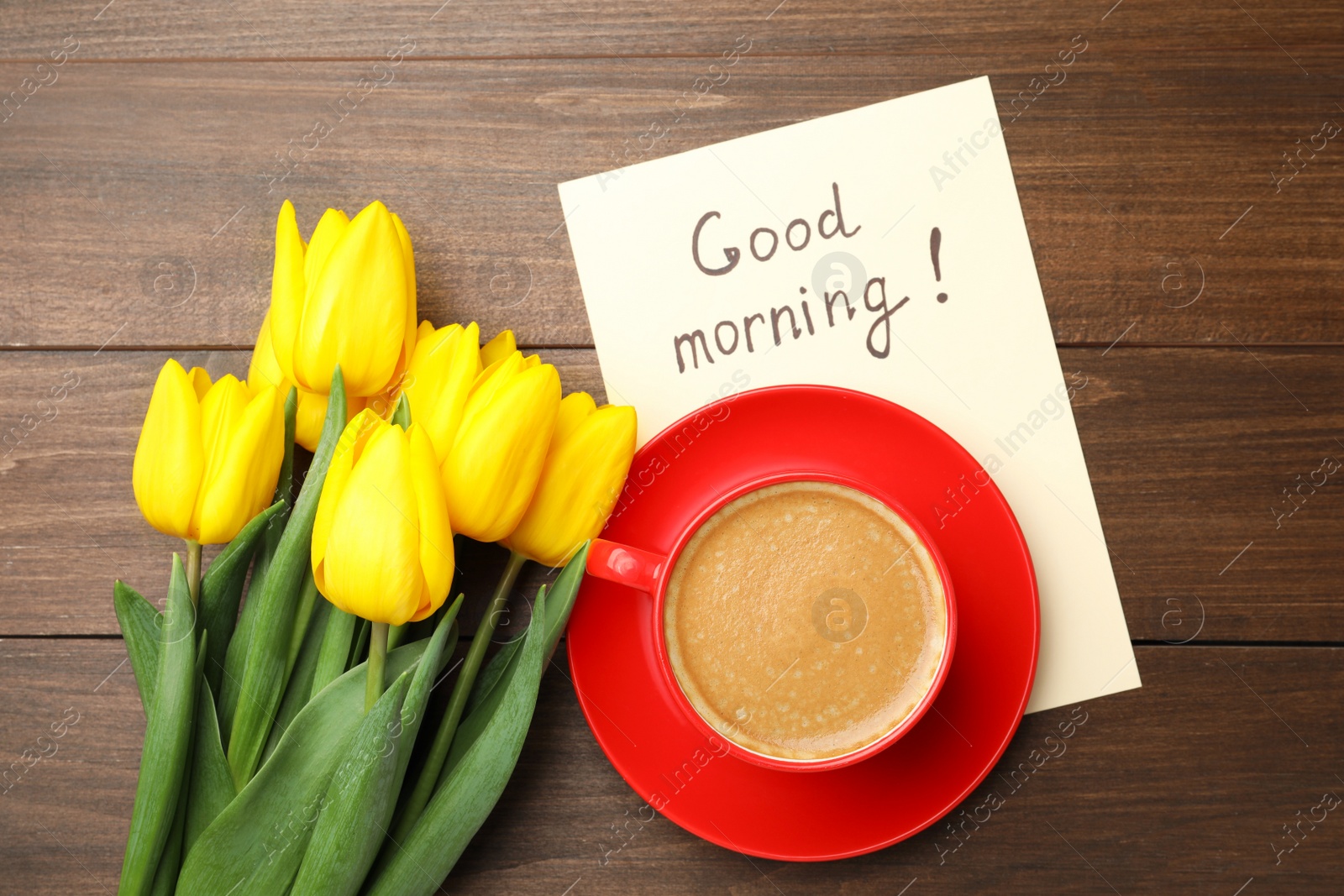 Photo of Beautiful yellow tulips, cup of aromatic coffee and Good Morning note on wooden table, flat lay