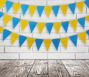 Image of Empty wooden table and decorative bunting flags hanging on white brick wall