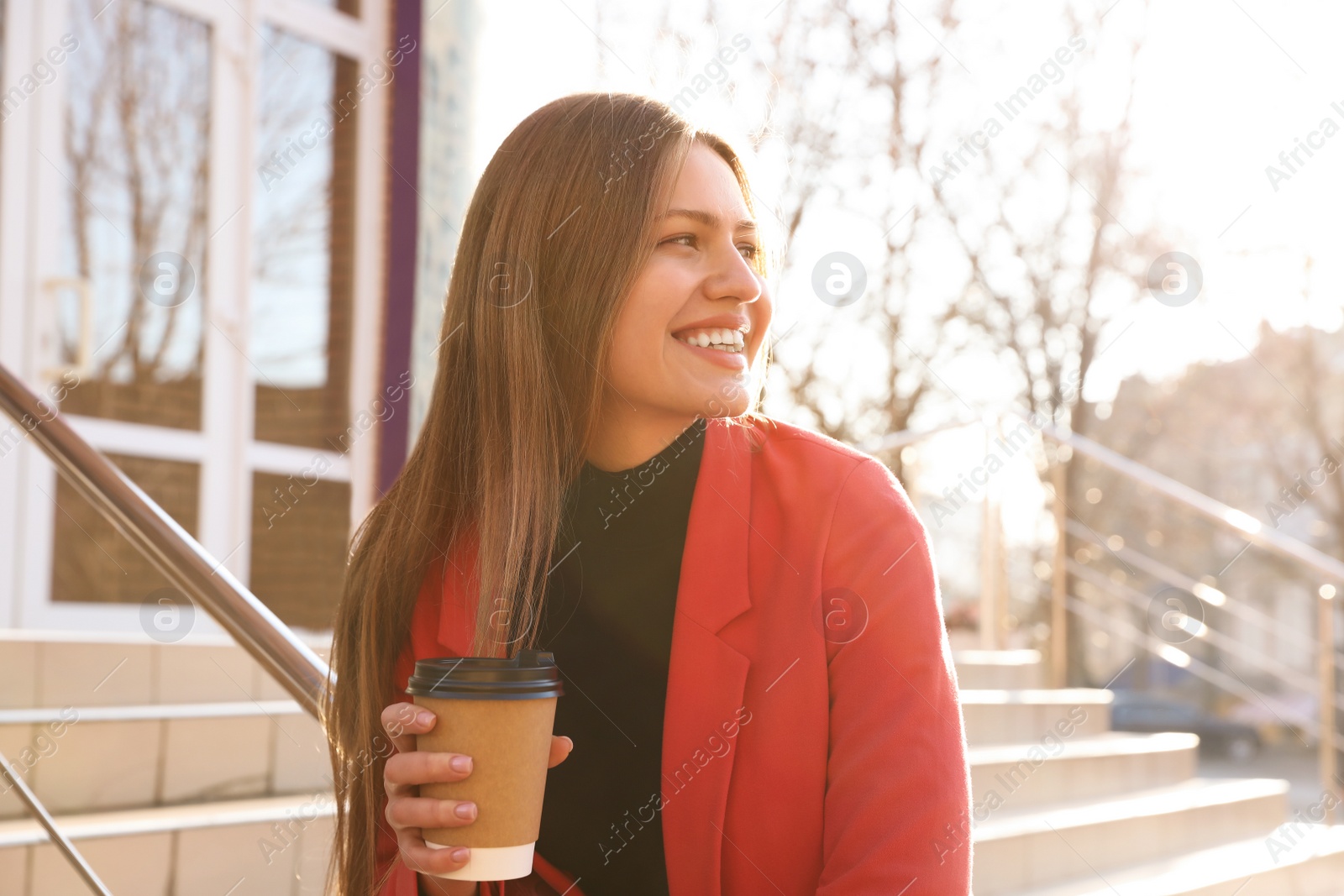 Photo of Businesswoman with cup of coffee on city street in morning