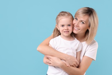 Photo of Family portrait of happy mother and daughter on light blue background. Space for text