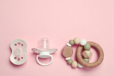 Flat lay composition with pacifiers and other baby stuff on pink background. Space for text