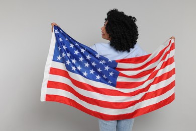 Photo of 4th of July - Independence Day of USA. Happy woman with American flag on light grey background, back view