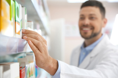 Image of Professional pharmacist near shelves in drugstore, focus on hand
