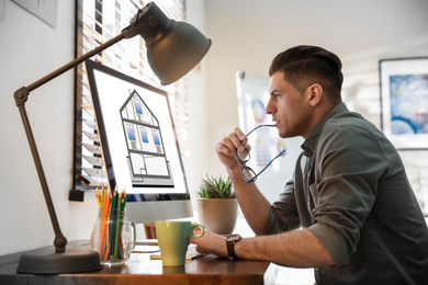 Engineer at work. Man projecting house in office