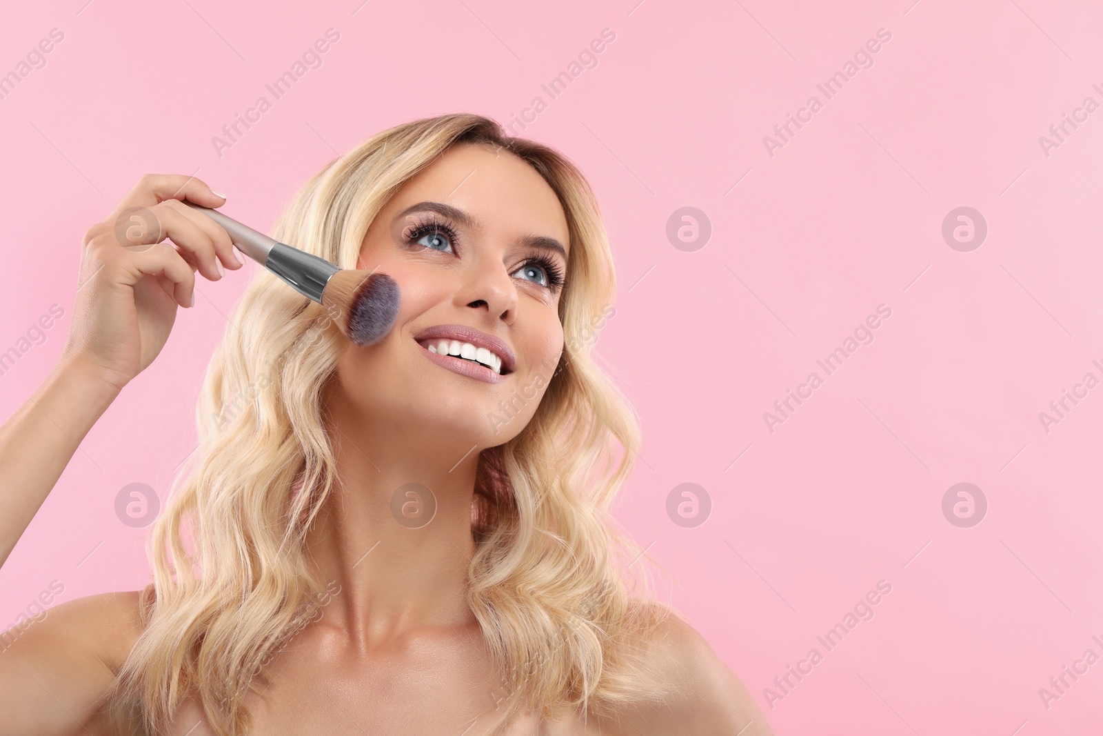 Photo of Beautiful makeup. Smiling woman with brush on pink background, space for text