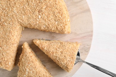 Photo of Taking piece of delicious Napoleon cake from table, top view