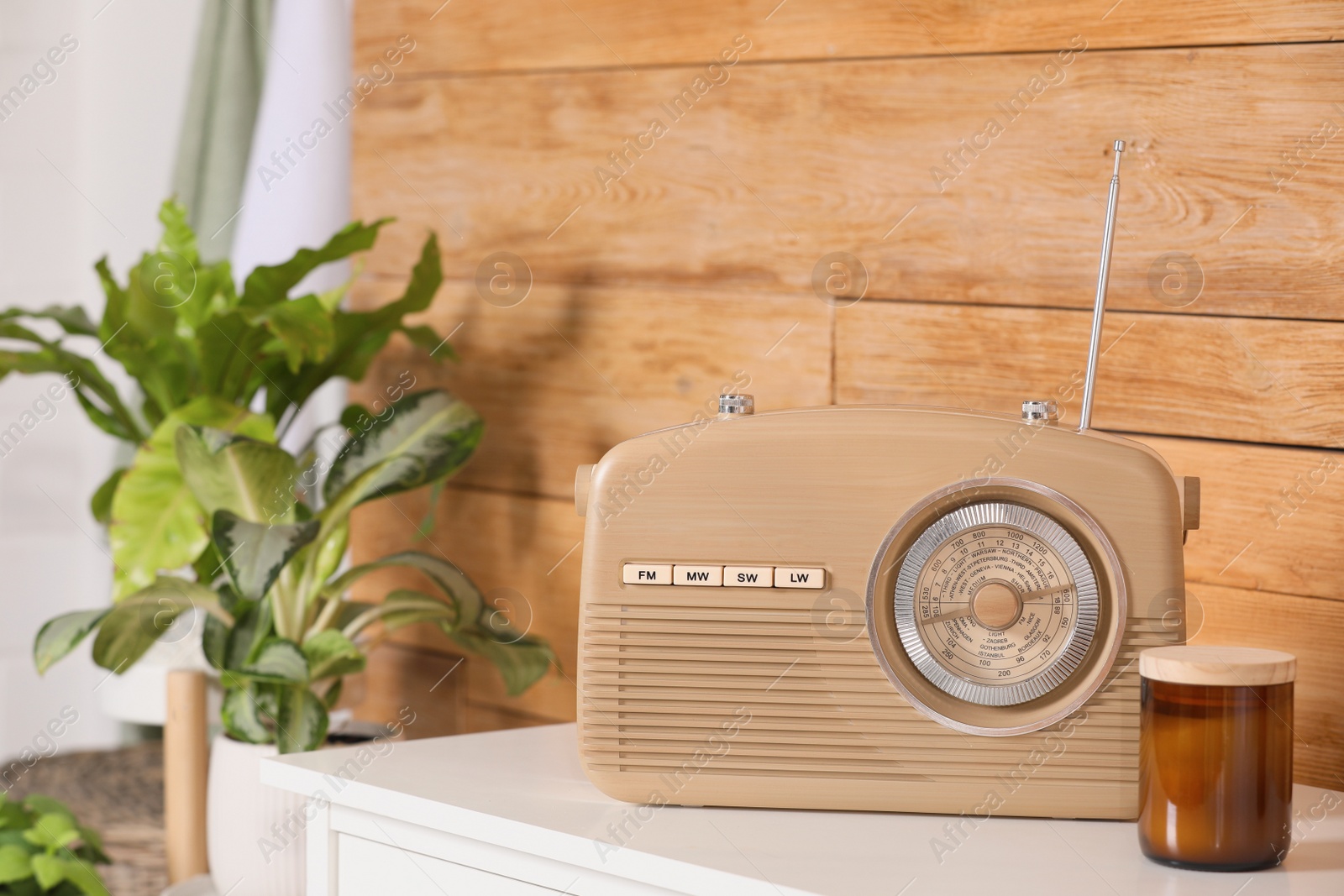 Photo of Stylish beige radio on white table near wooden wall indoors, space for text