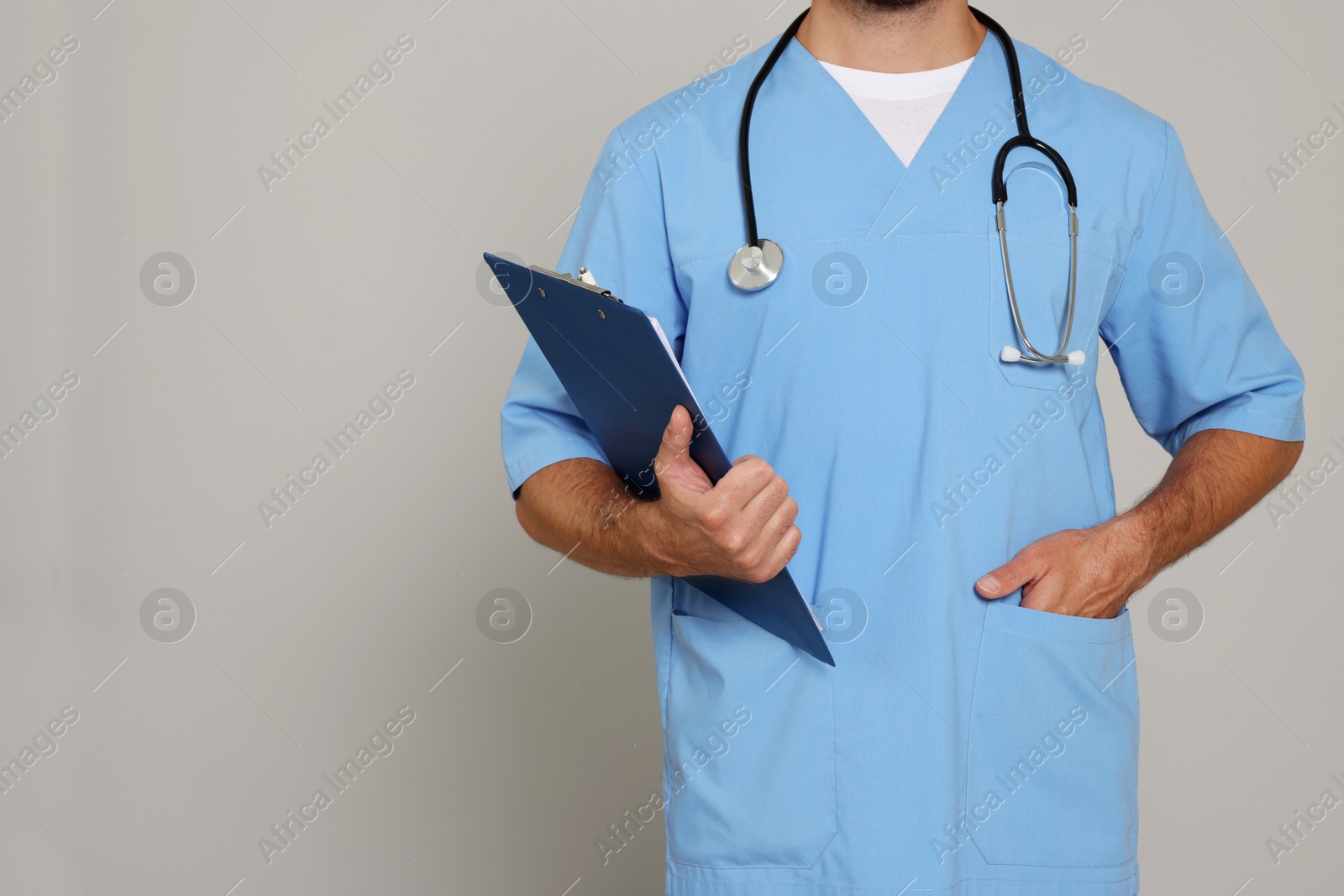 Photo of Doctor with stethoscope and clipboard on light grey background, closeup