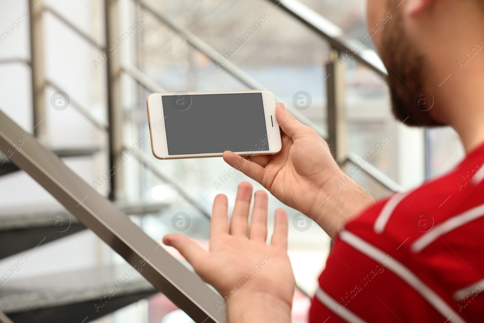 Photo of Young man using video chat on smartphone indoors, closeup. Space for design