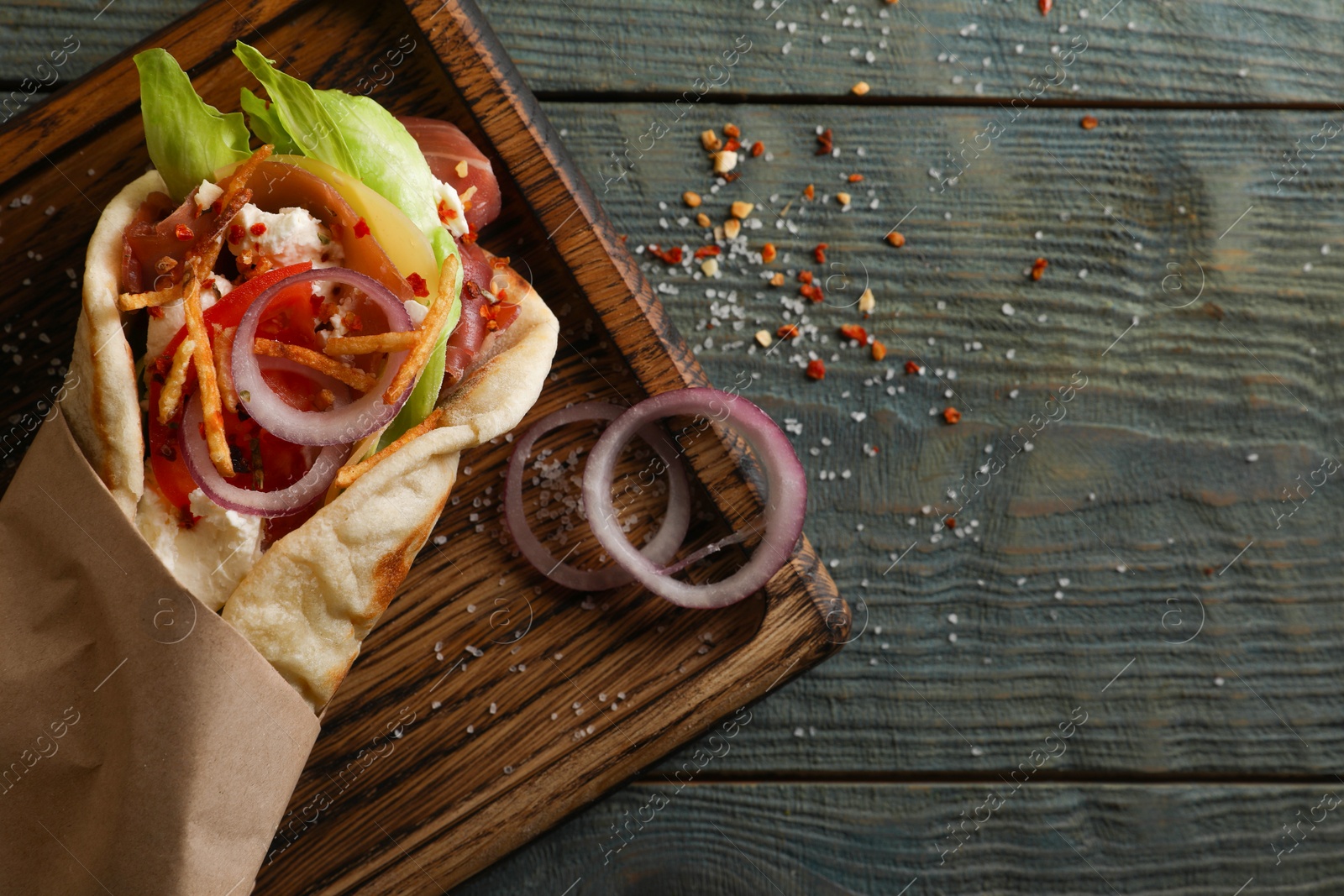 Photo of Delicious pita wrap with vegetables and meat on dark wooden table, top view. Space for text