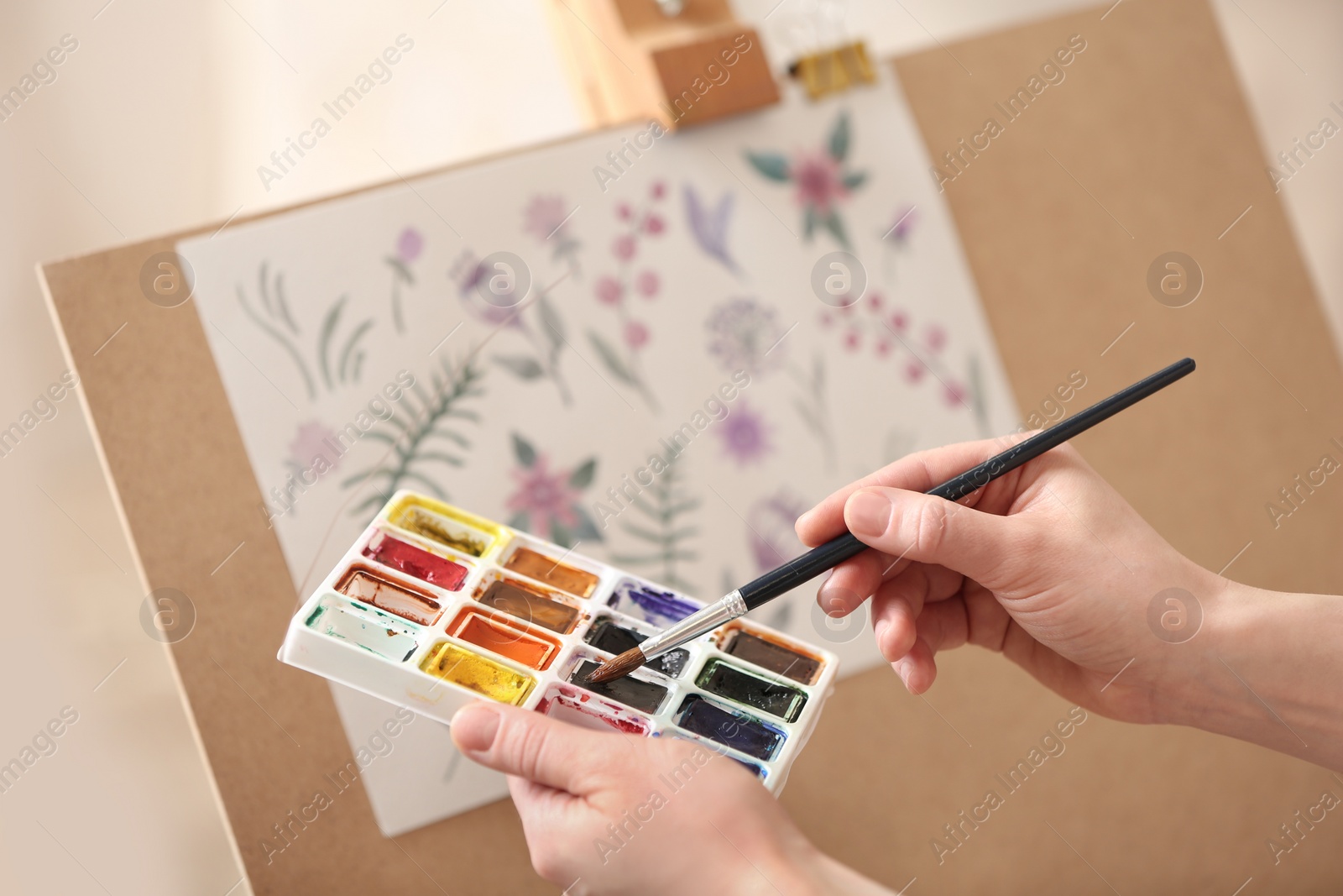 Photo of Woman painting flowers with watercolors in workshop, closeup