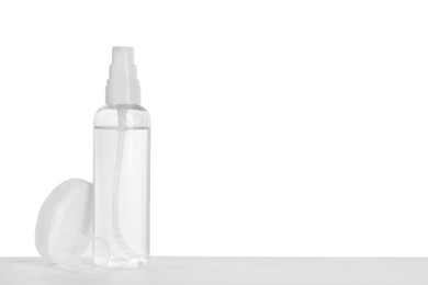 Photo of Micellar water and cotton pads on table against white background. Space for text
