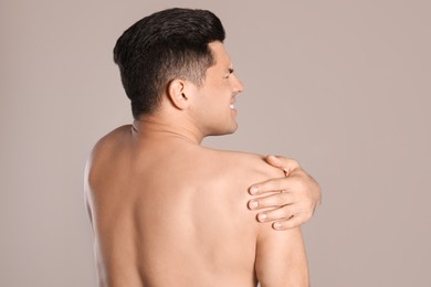 Photo of Man suffering from shoulder pain on beige background, back view