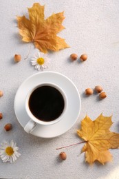 Flat lay composition with cup of hot drink and autumn leaves on light grey textured table