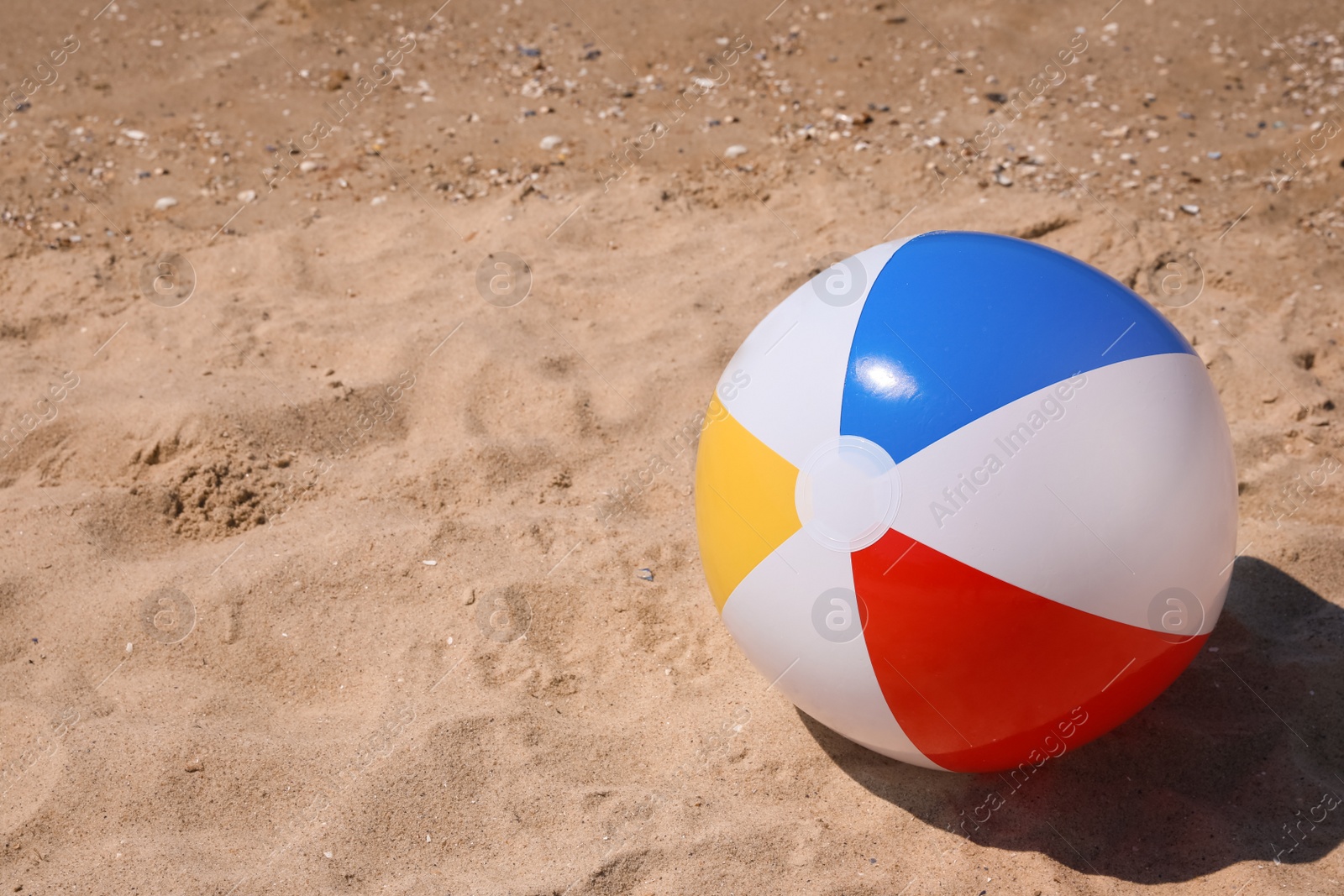 Photo of Colorful inflatable ball on sandy beach. Space for text