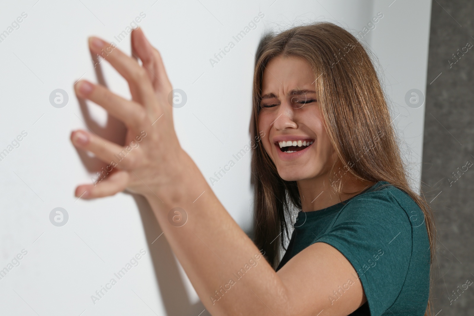 Photo of Portrait of crying young woman near light wall. Stop violence