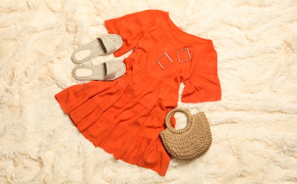 Flat lay composition with stylish bright dress on beige blanket